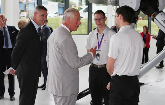 His Royal Highness The Prince of Wales speaking to hardware test engineers with Robin Glover-Faure, President of L3Harris Commercial Training Solutions in the background.